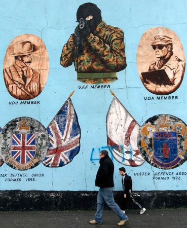 Father and Son walk past a mural in Belfast